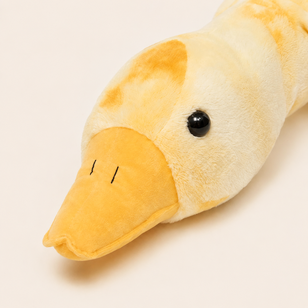 Gros plan du visage, du bec orange et de la texture de la peluche oie jaune