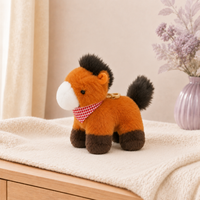 Petit cheval en peluche orange posé dans un intérieur clair