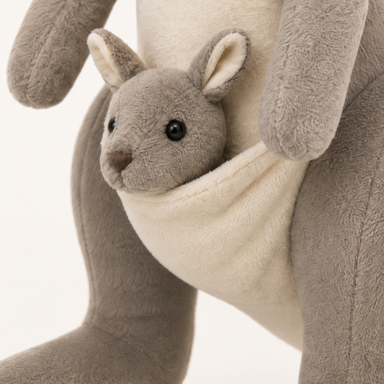 Gros plan sur le bébé kangourou et la poche ivoire de la peluche gris foncé