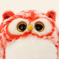Gros plan sur les yeux ambrés et la fourrure de la peluche hibou rouge