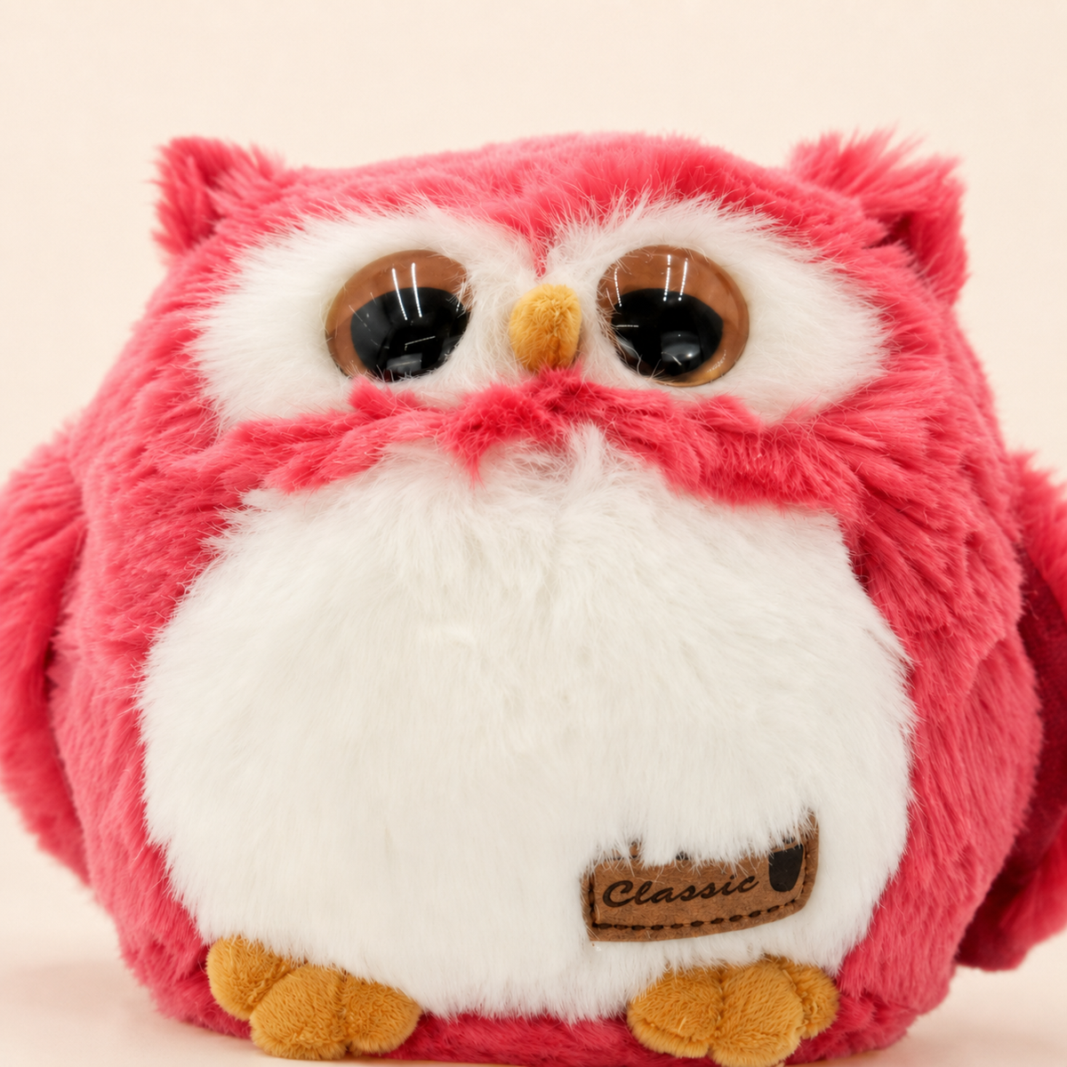 Gros plan sur le visage les yeux et la fourrure de la peluche hibou framboise