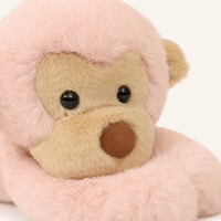Gros plan sur le visage beige et la fourrure rose de la peluche singe