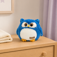 Peluche hibou bleue posée sur une commode en bois clair