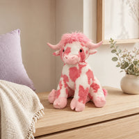 Peluche vache Highland rose posee sur une commode, mise en situation