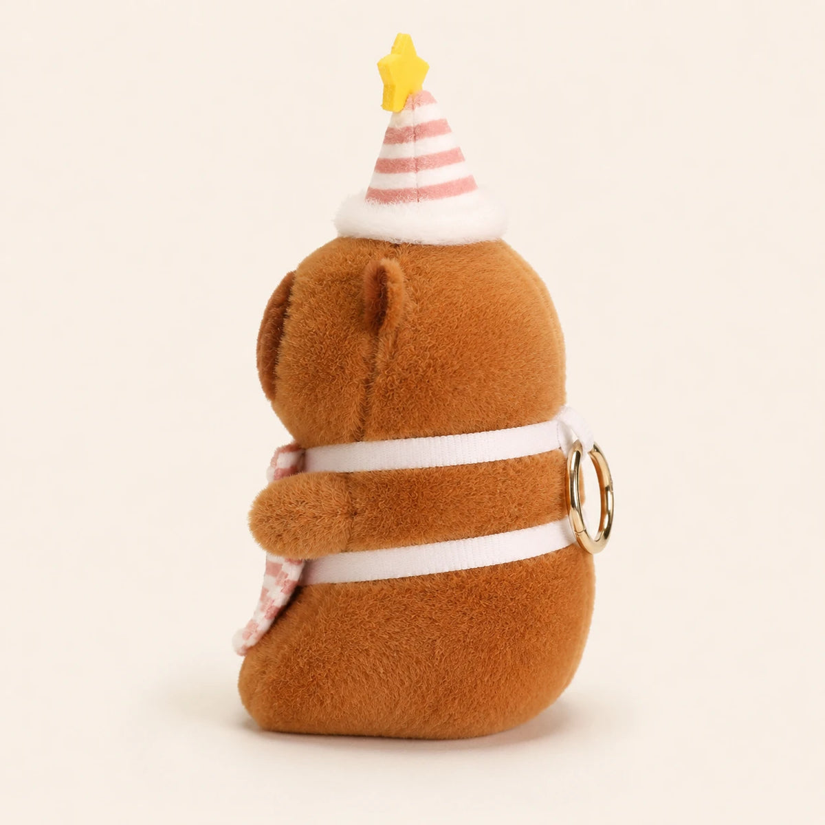 Peluche capybara au chapeau de fete vue de dos, fond ivoire