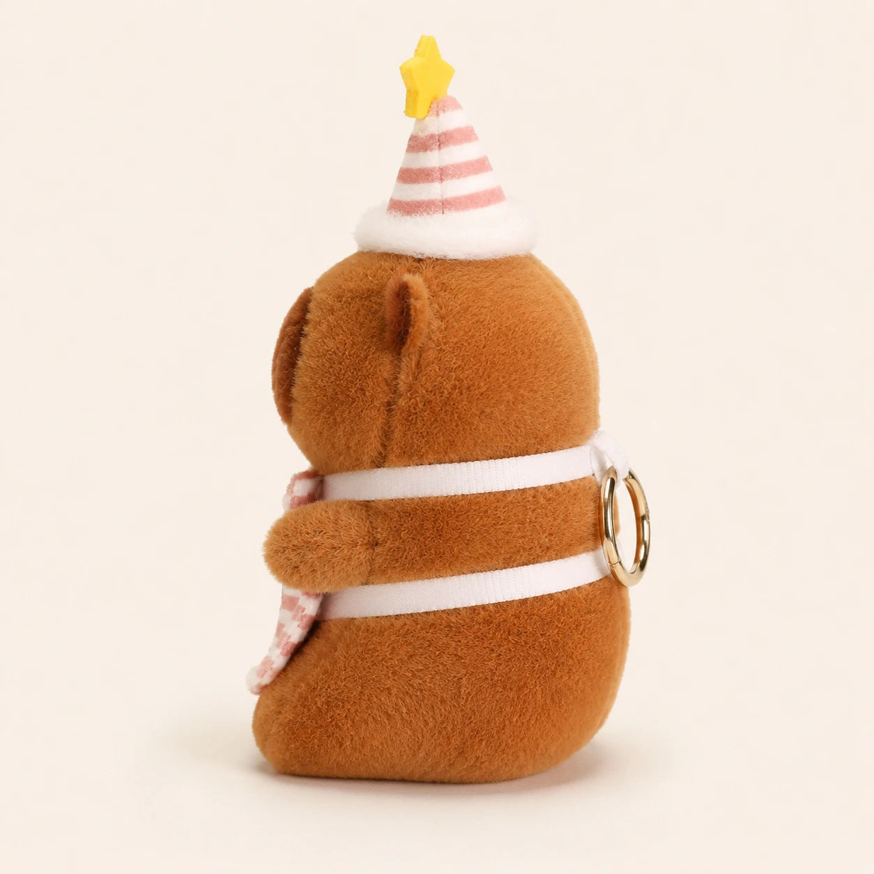 Peluche capybara au chapeau de fete vue de dos, fond ivoire