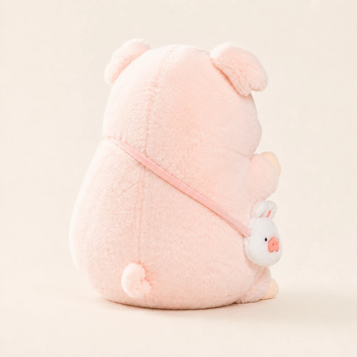Peluche cochon rose vue de dos, fond ivoire