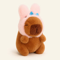 Peluche capybara avec bonnet a oreilles de lapin, environ 12 cm, fond ivoire