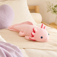 Peluche axolotl rose posée sur un lit douillet, mise en situation