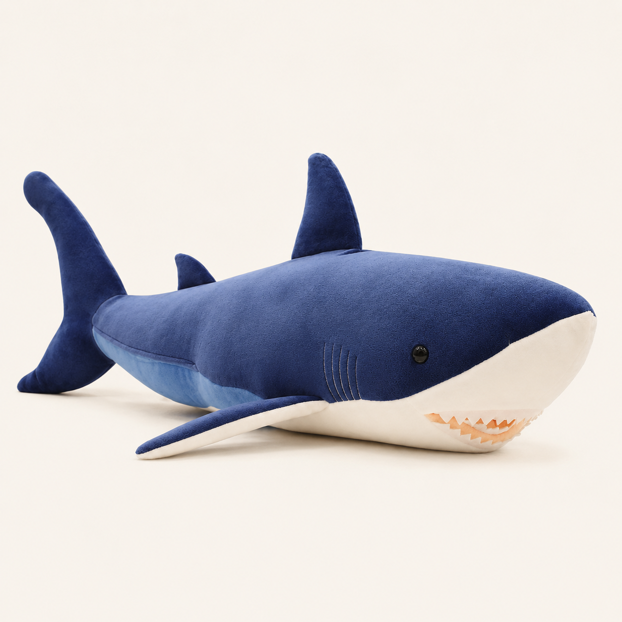 Peluche requin bleu vue de côté, fond ivoire