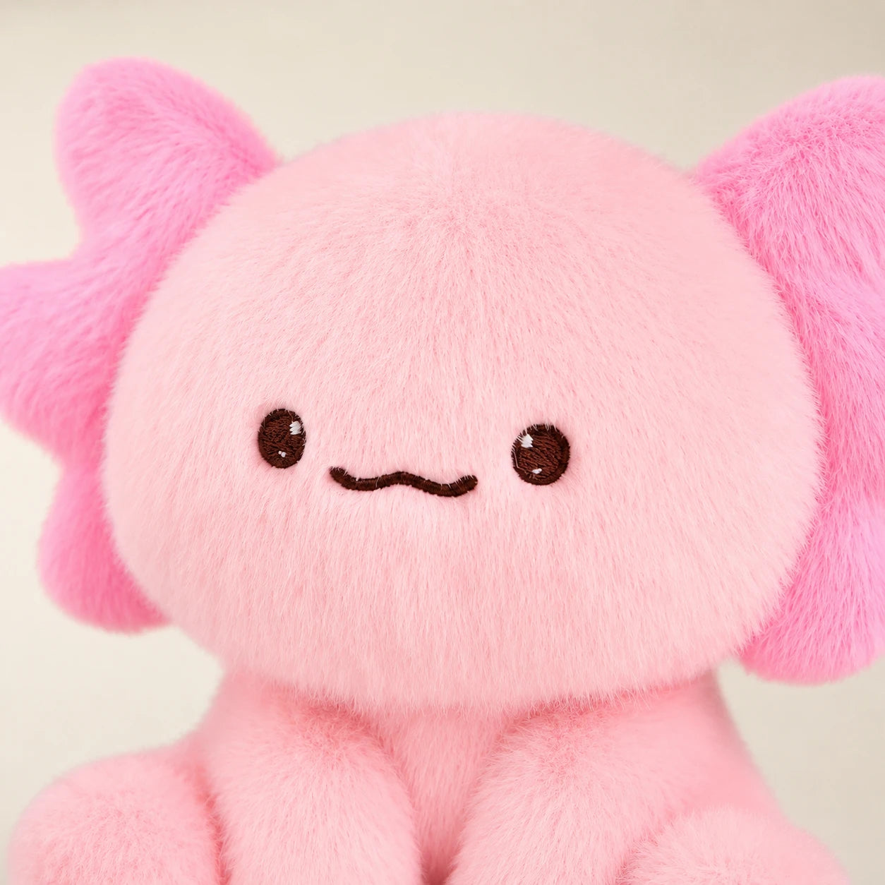 Gros plan sur le visage et la texture douce de la peluche axolotl