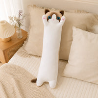 Coussin peluche chat posé sur un lit