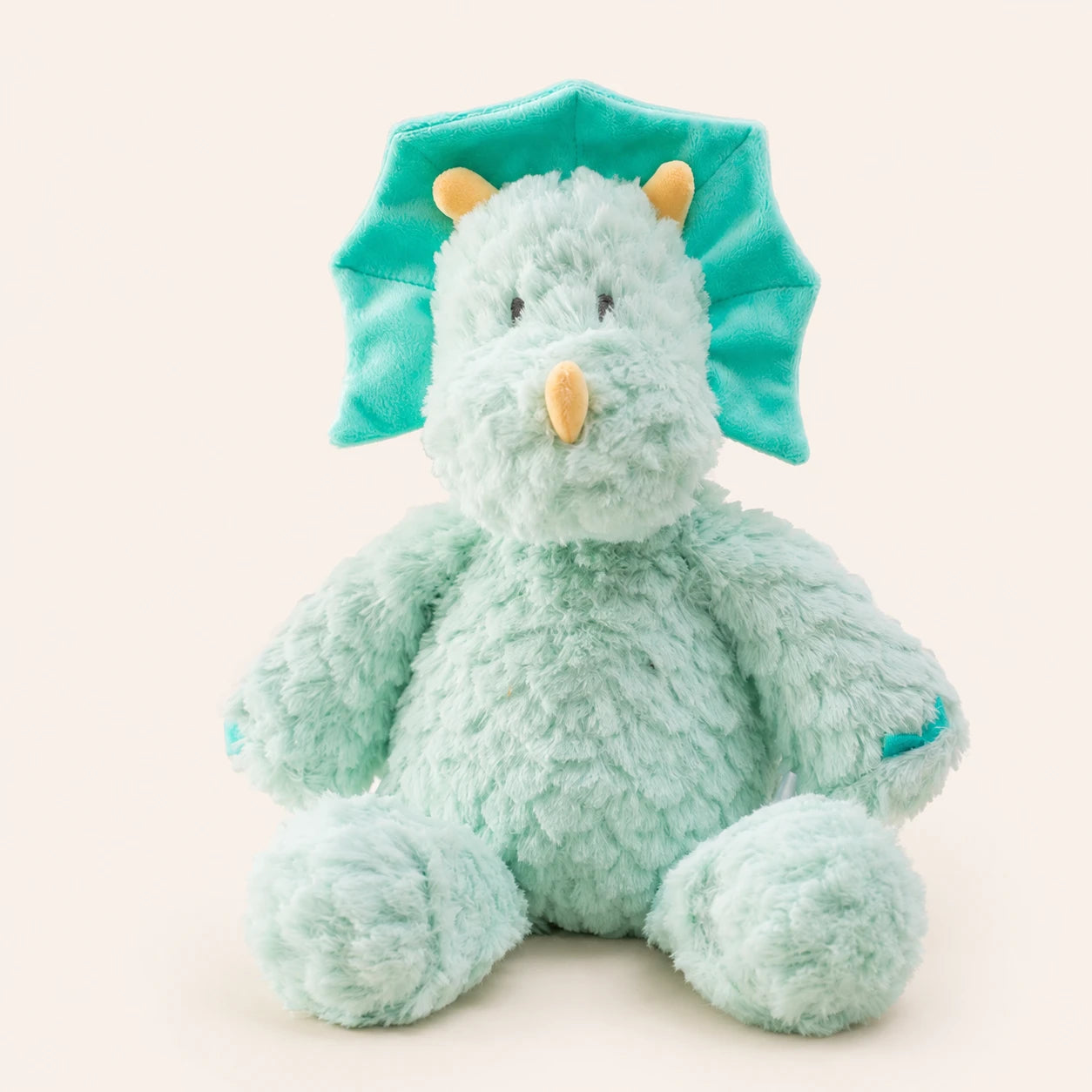 Peluche dinosaure bleu vert à longues pattes, vue de face sur fond ivoire