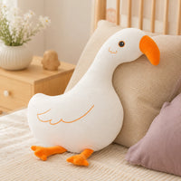 Coussin peluche oie posé sur un lit douillet