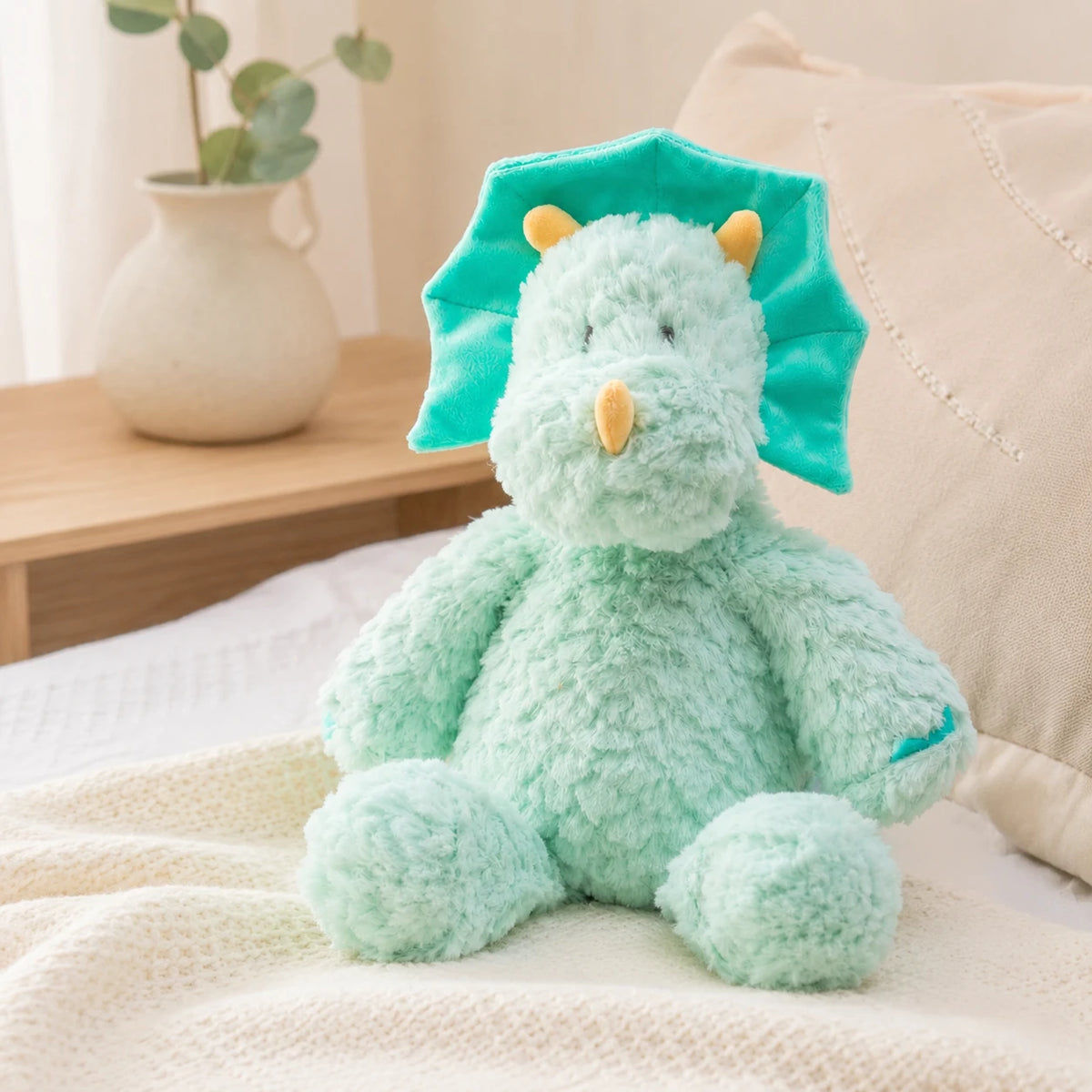 Peluche dinosaure bleu vert posée sur un lit douillet dans une chambre chaleureuse