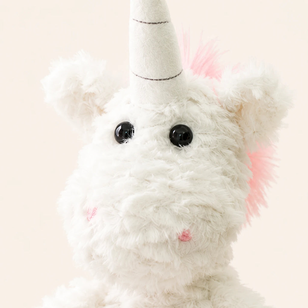 Gros plan sur le visage et la corne de la peluche licorne