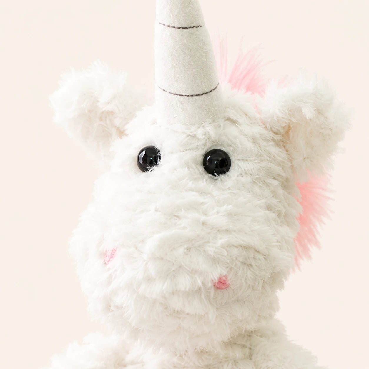 Gros plan sur le visage et la corne de la peluche licorne