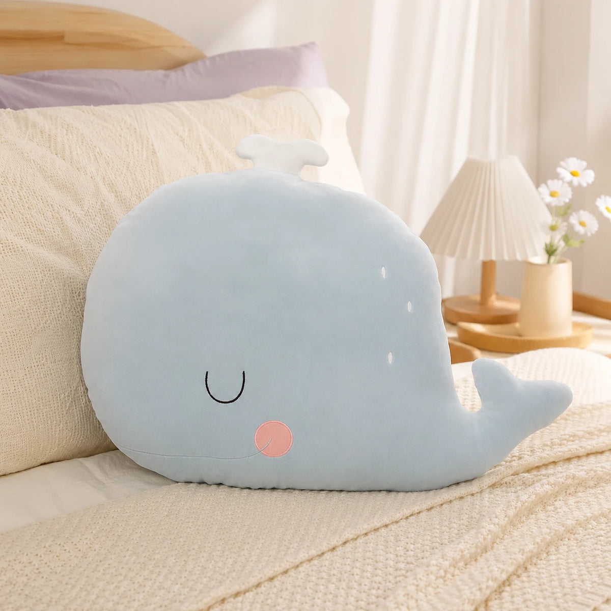 Coussin peluche baleine posé sur un lit