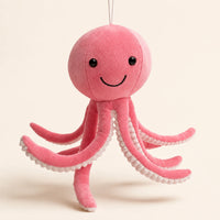 Peluche pieuvre rose à longues pattes, fond beige ivoire