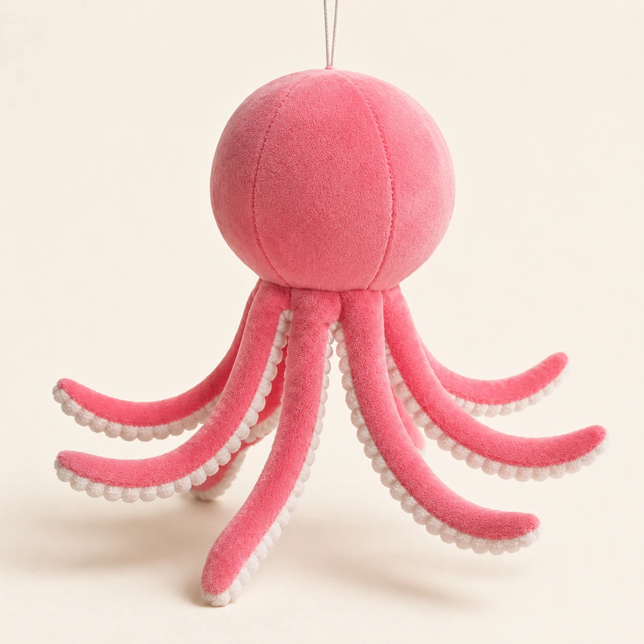 Peluche pieuvre rose vue de côté, fond ivoire