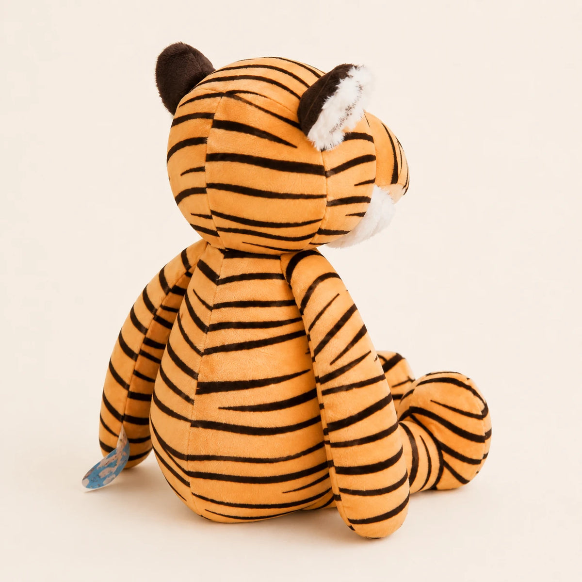 Peluche tigre rayé vue de trois-quarts, fond ivoire