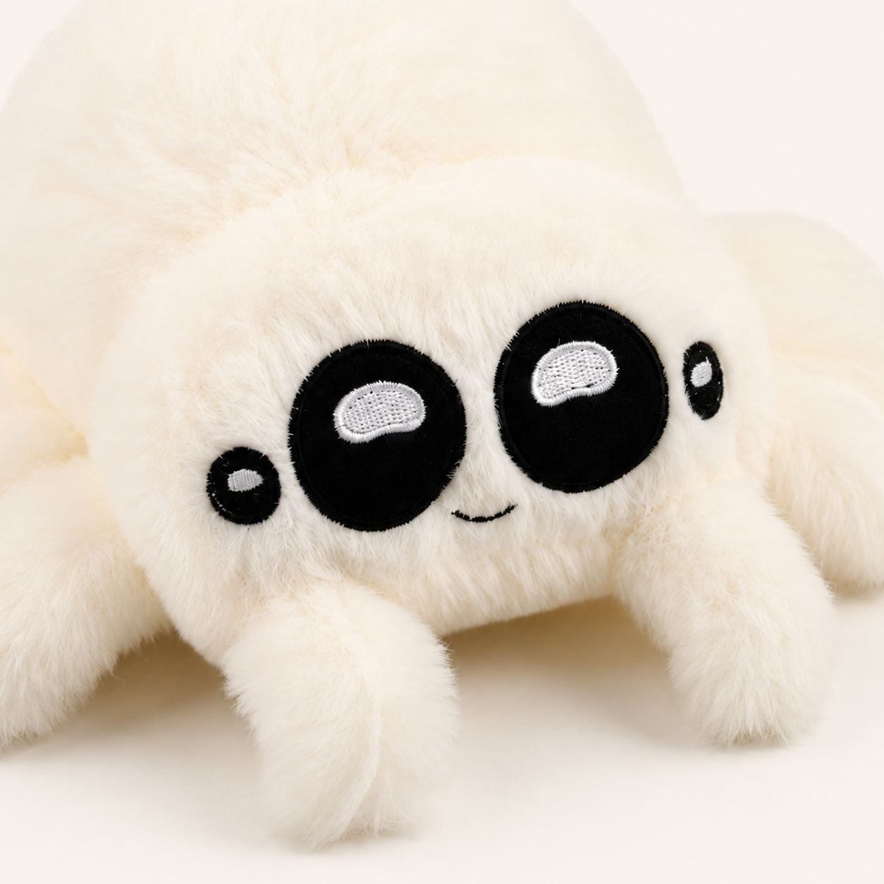 Peluche araignée blanche, détail du visage et des yeux