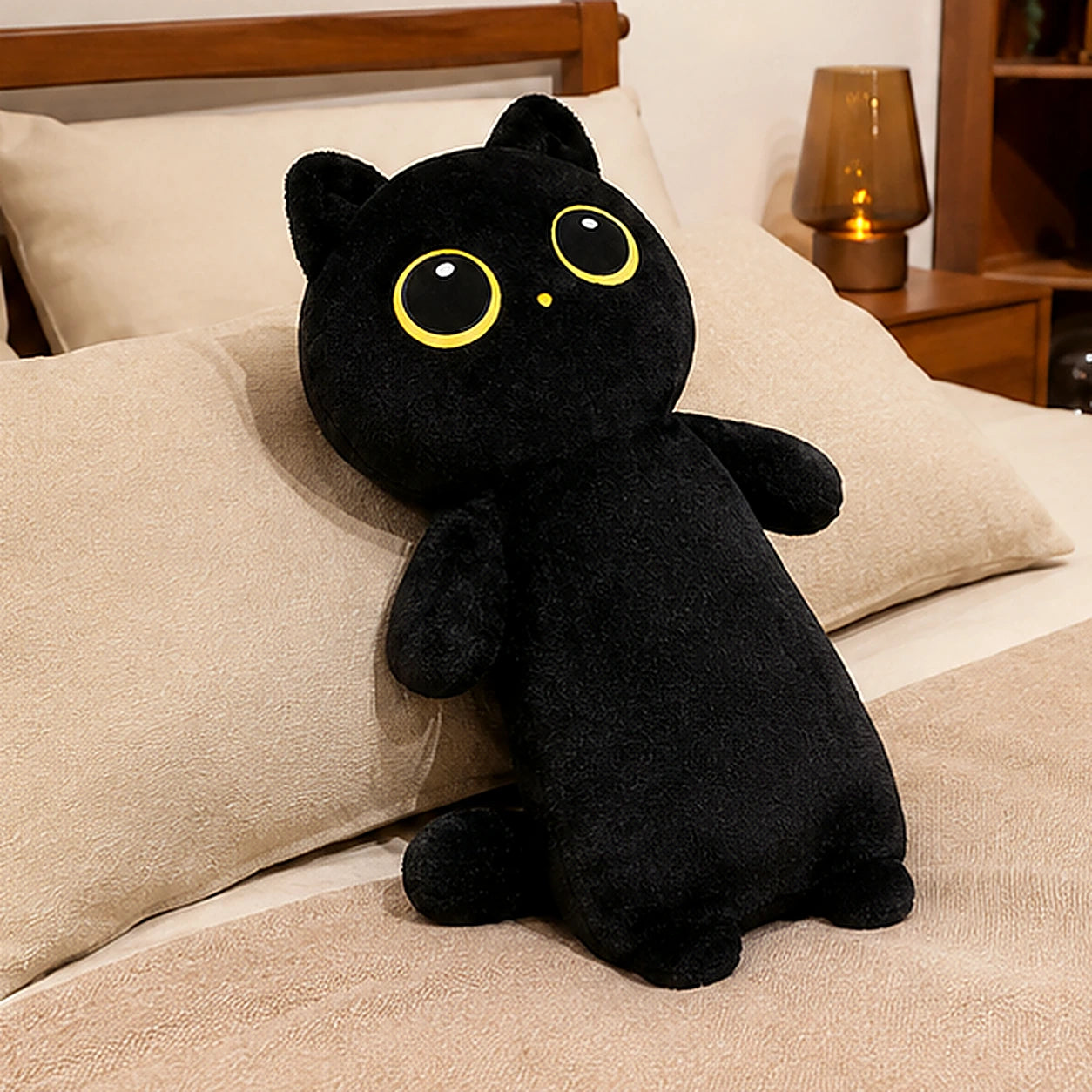 Peluche coussin chat noir en situation sur lit