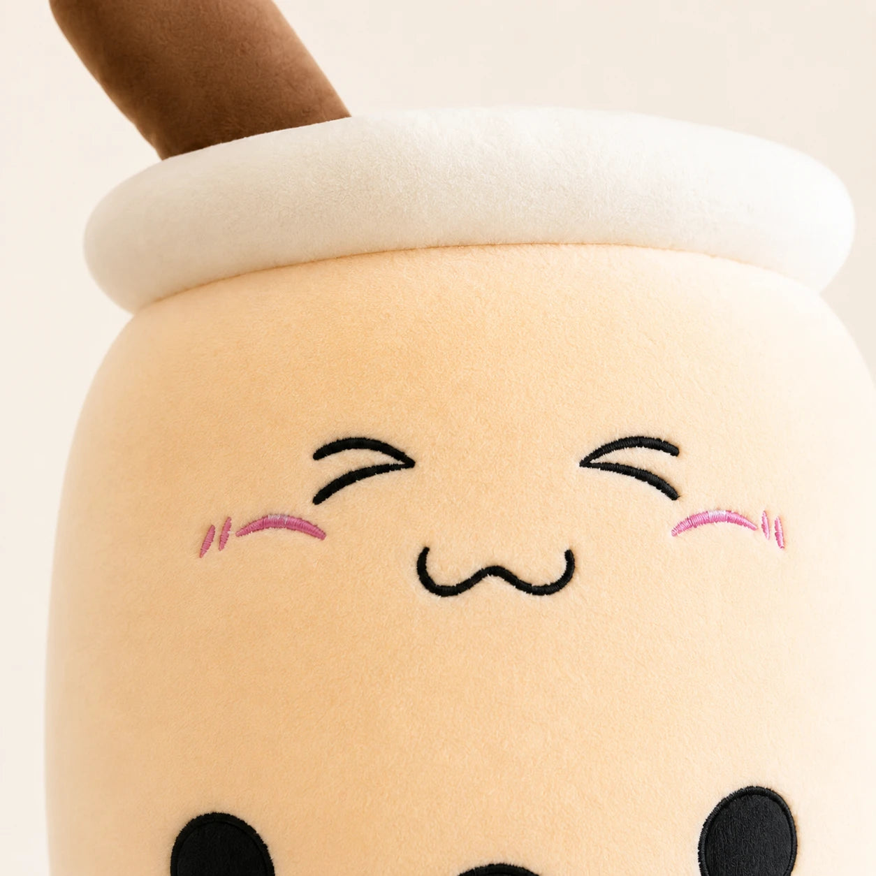 Gros plan sur le visage kawaii et la texture douce de la peluche boba beige