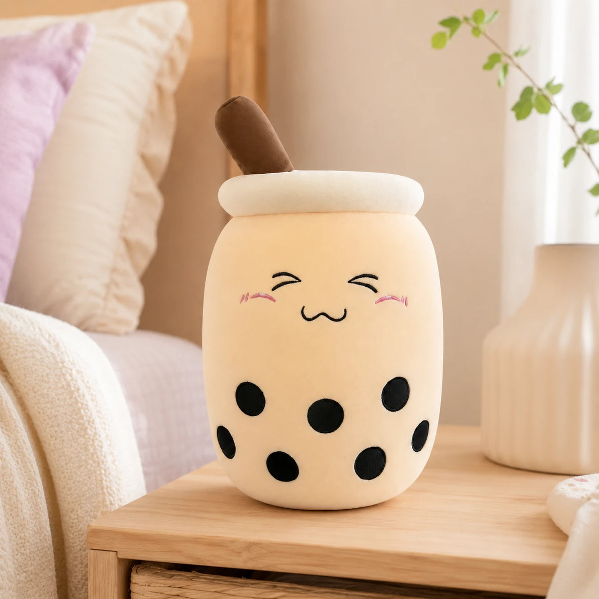 Peluche bubble tea boba beige posee sur une table de chevet dans une chambre cosy