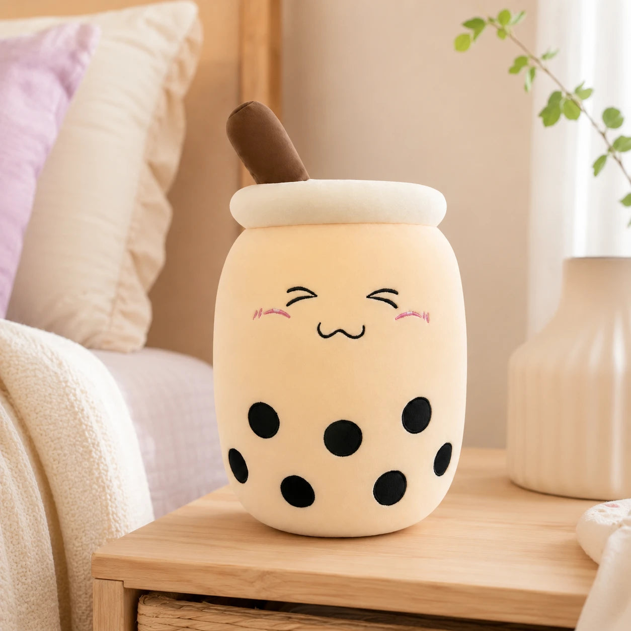 Peluche bubble tea boba beige posee sur une table de chevet dans une chambre cosy
