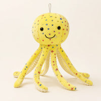Peluche pieuvre jaune à étoiles multicolores, vue de face sur fond ivoire