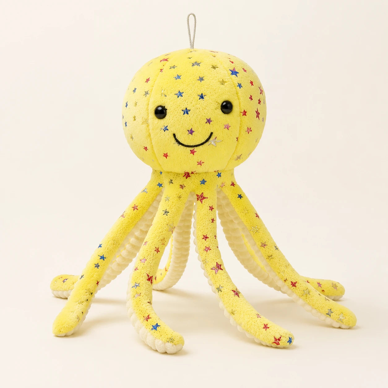 Peluche pieuvre jaune à étoiles multicolores, vue de face sur fond ivoire