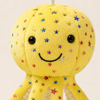 Gros plan sur le visage souriant et les étoiles brodées de la peluche pieuvre