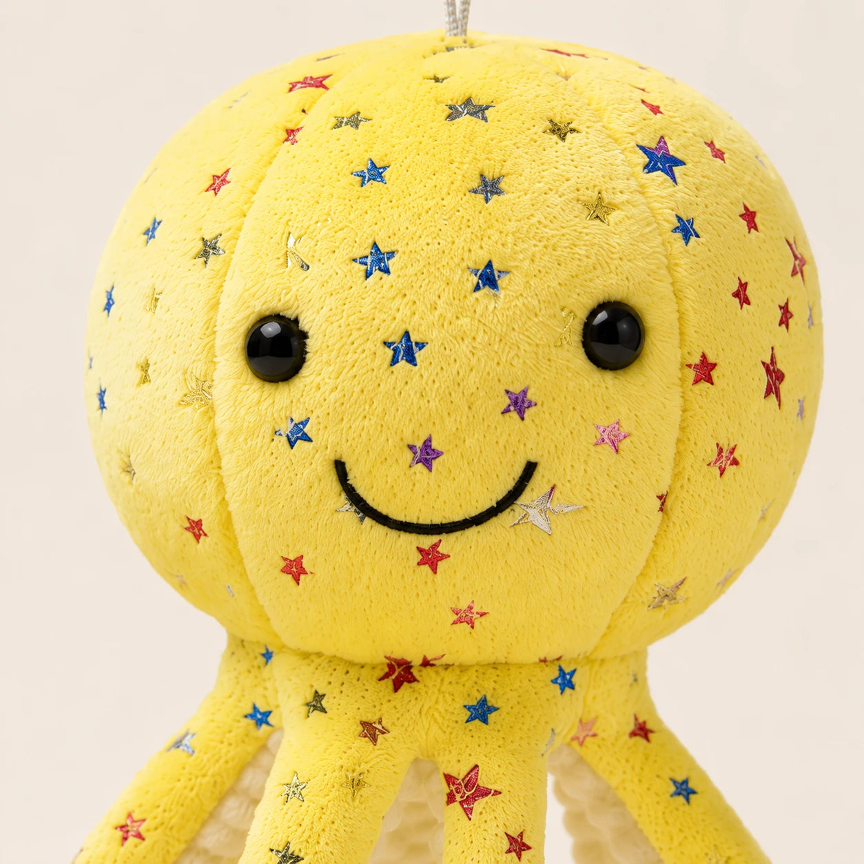 Gros plan sur le visage souriant et les étoiles brodées de la peluche pieuvre