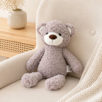 Ours en peluche posé sur un fauteuil crème dans un intérieur chaleureux