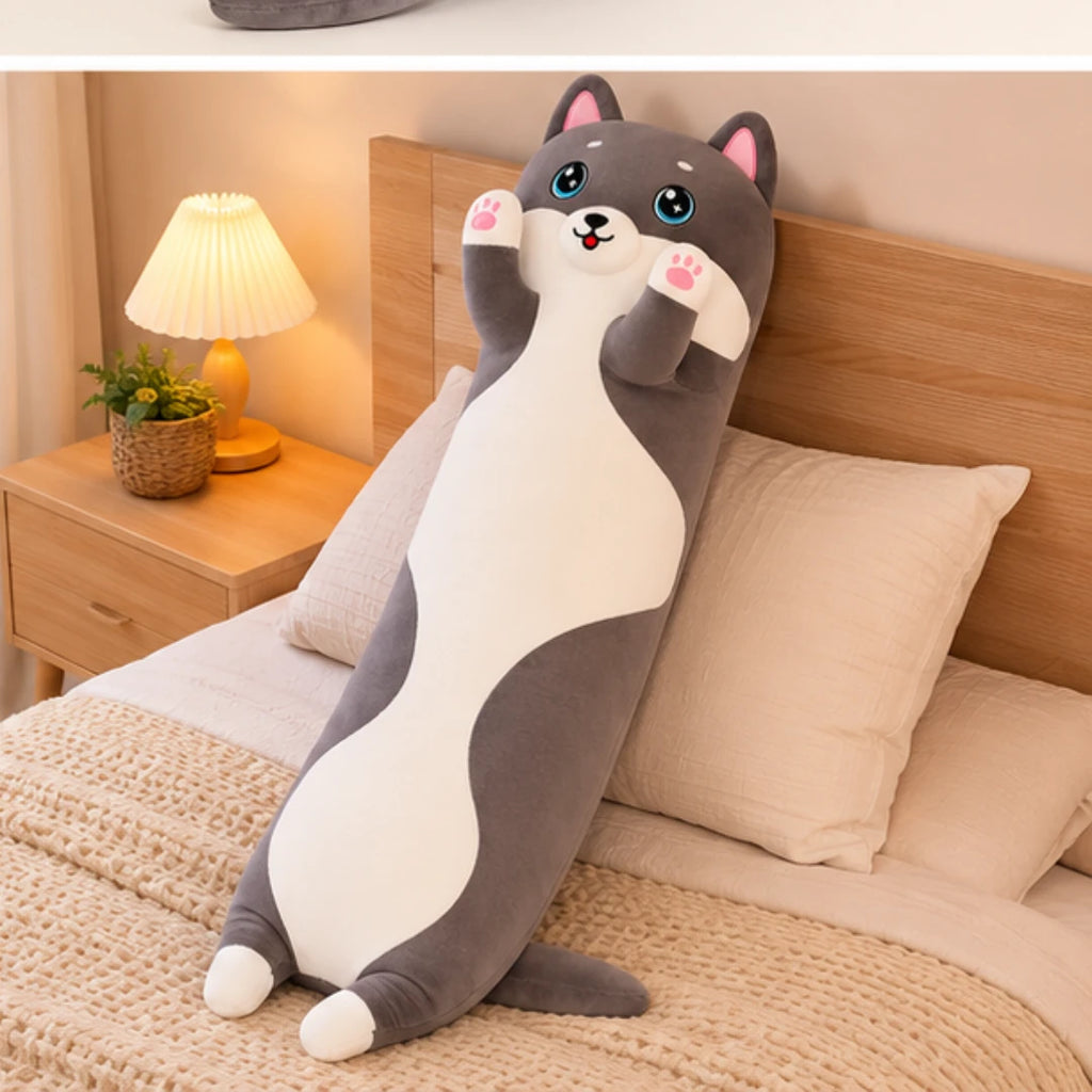 Peluche longue chat posée en situation sur un lit cosy