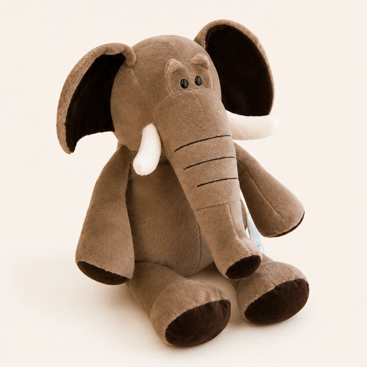 Peluche éléphant grise vue de trois-quarts sur fond ivoire