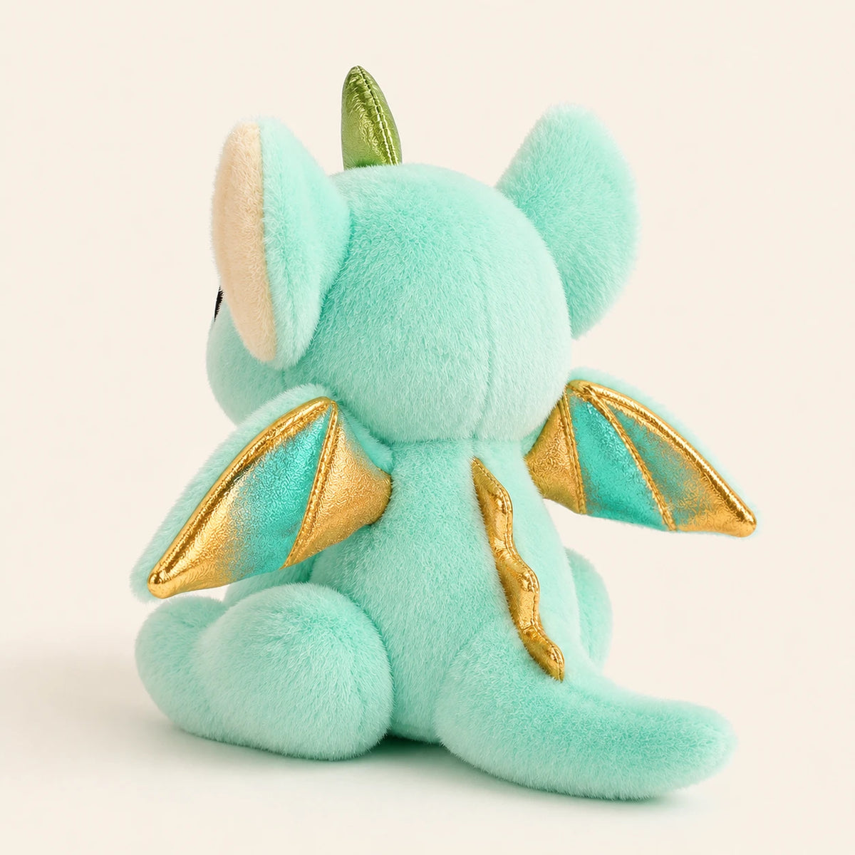 Peluche dragon vue de trois-quarts arrière montrant les ailes dorées