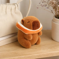 Peluche capybara bouée orange en situation sur une table - Royaume Peluche