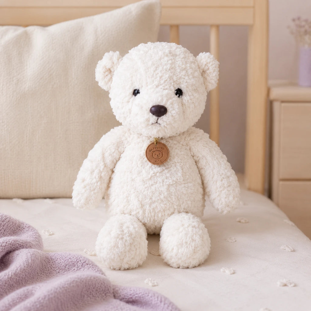 Peluche ours blanc longues pattes 35 cm posée sur un lit