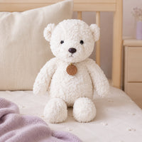 Peluche ours blanc longues pattes 35 cm posée sur un lit