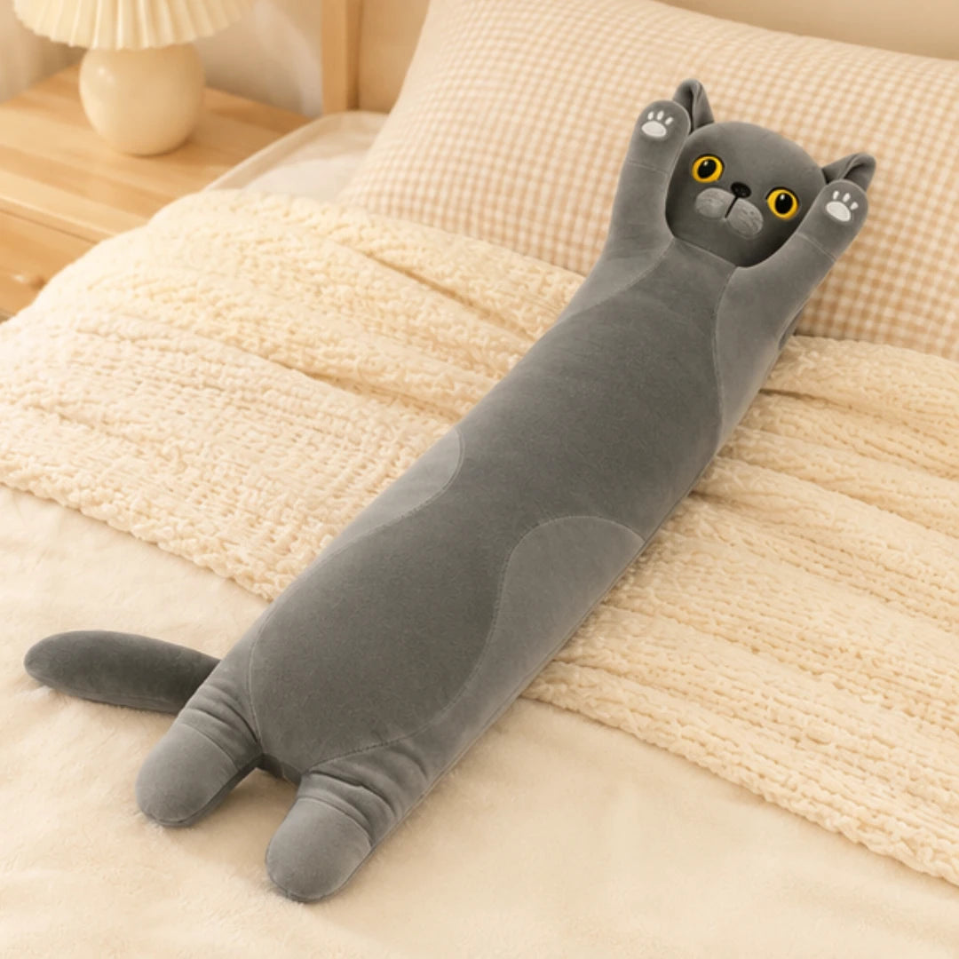 Peluche longue chat posée en situation sur un lit cosy