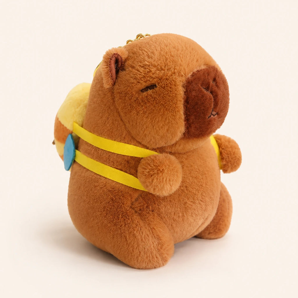 Peluche capybara brun avec petit sac à dos, vue de face sur fond ivoire