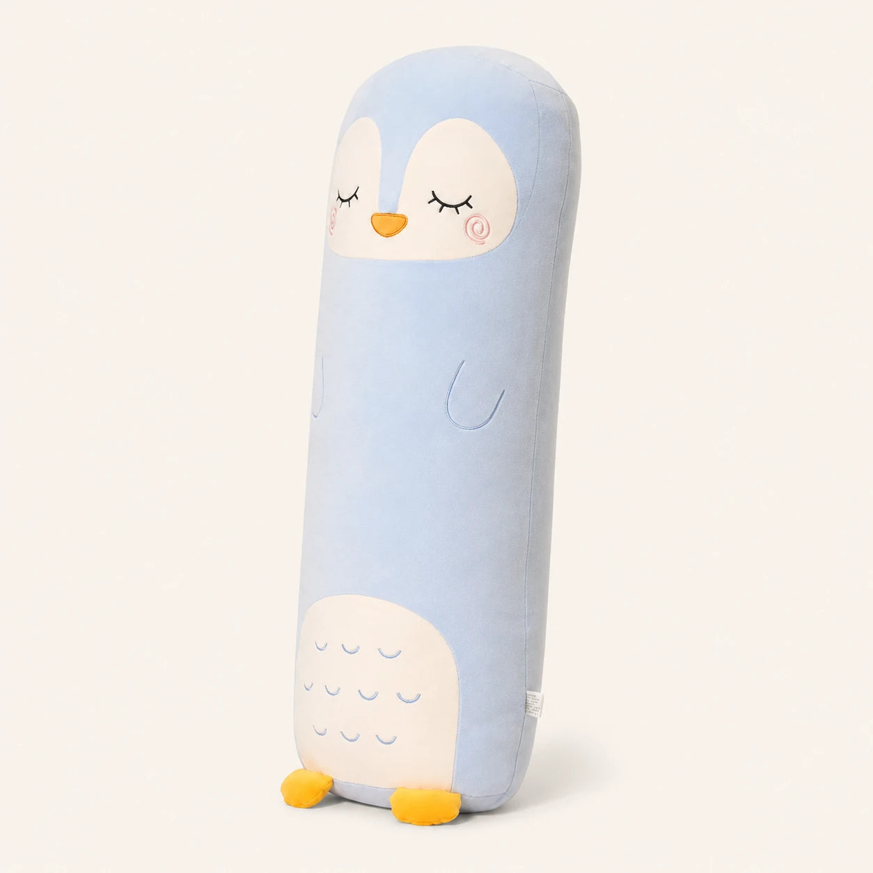 Coussin long peluche pingouin vu de trois-quarts sur fond ivoire