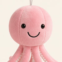 Gros plan sur le visage souriant de la peluche pieuvre rose