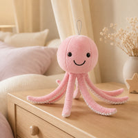 Peluche pieuvre rose posée sur une commode dans une chambre