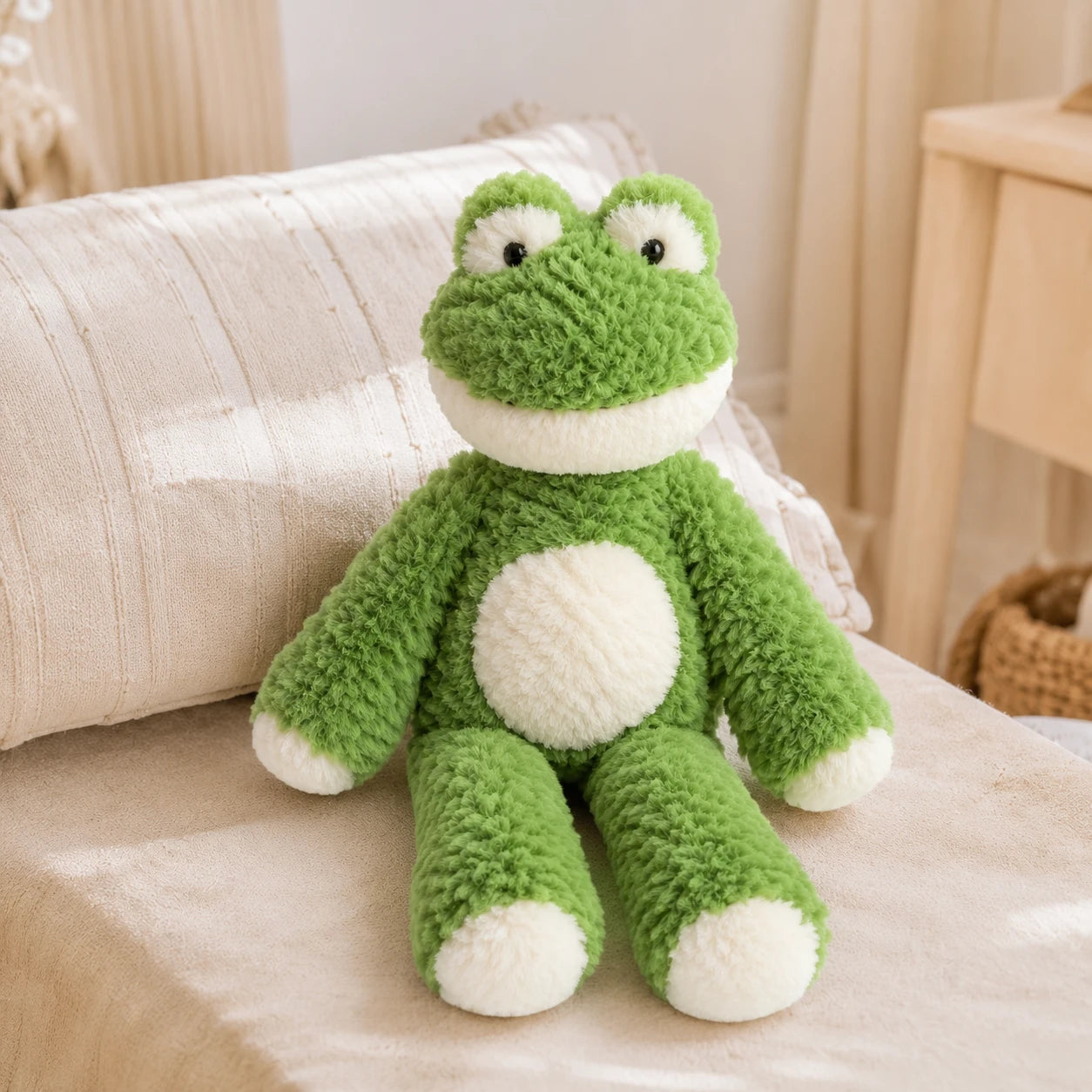Peluche grenouille longues pattes 35 cm posée sur un lit