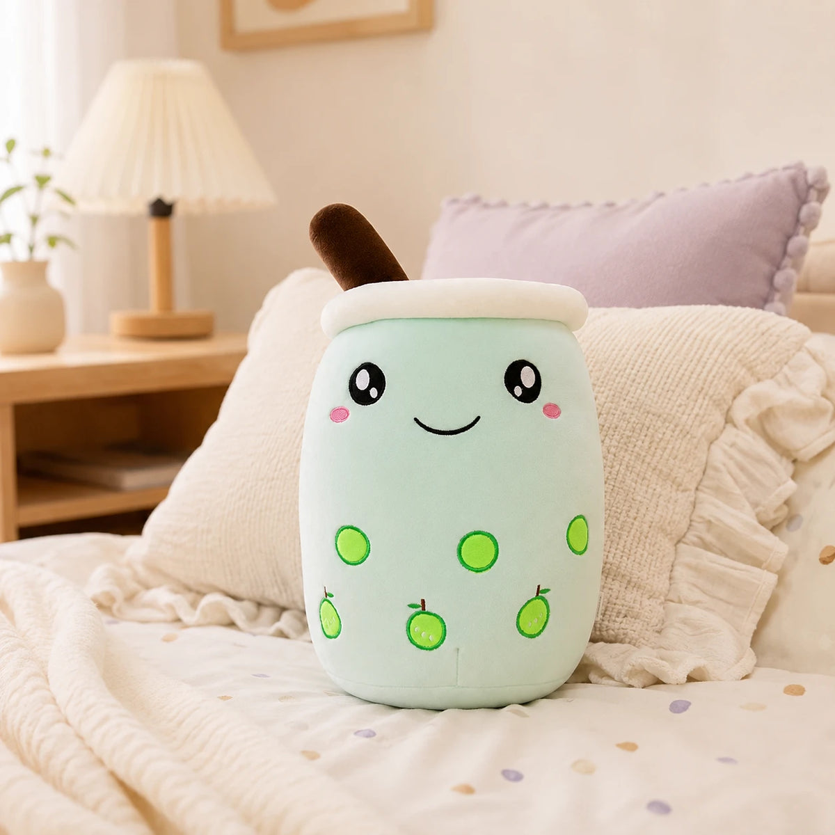 Peluche bubble tea vert pomme posee sur un lit douillet, ambiance chaleureuse