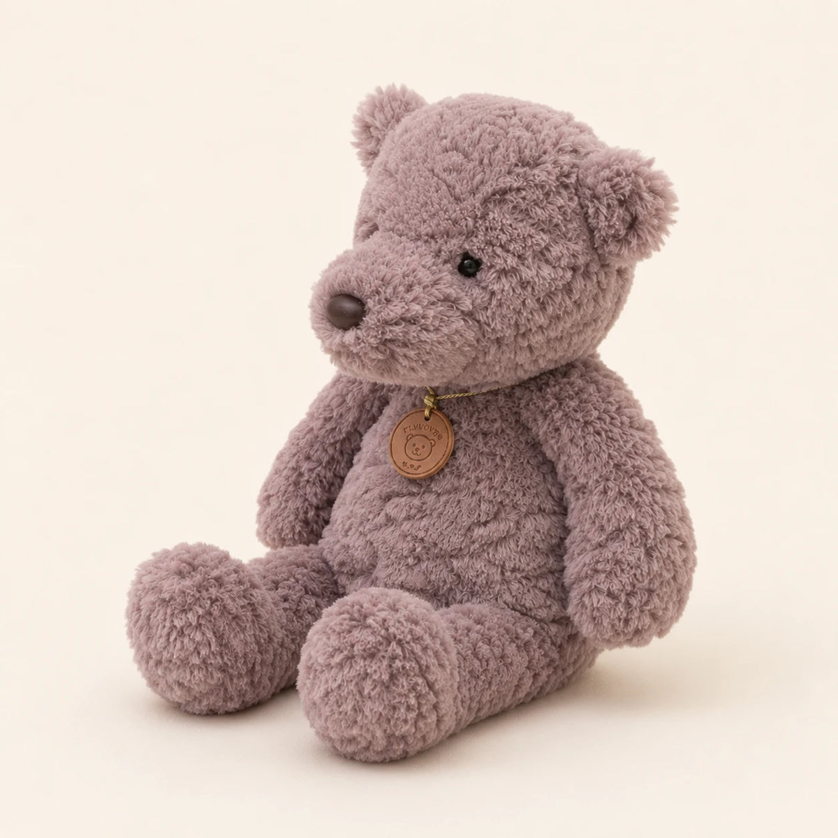 Peluche ours gris vue de trois-quarts sur fond ivoire