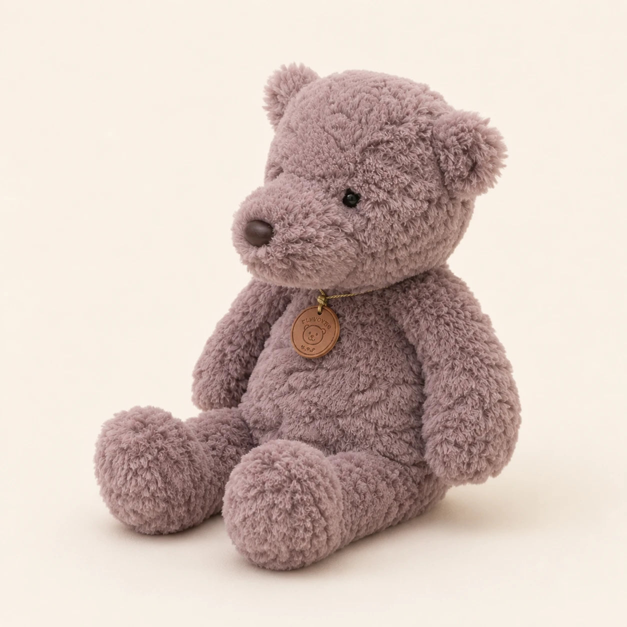 Peluche ours gris vue de trois-quarts sur fond ivoire